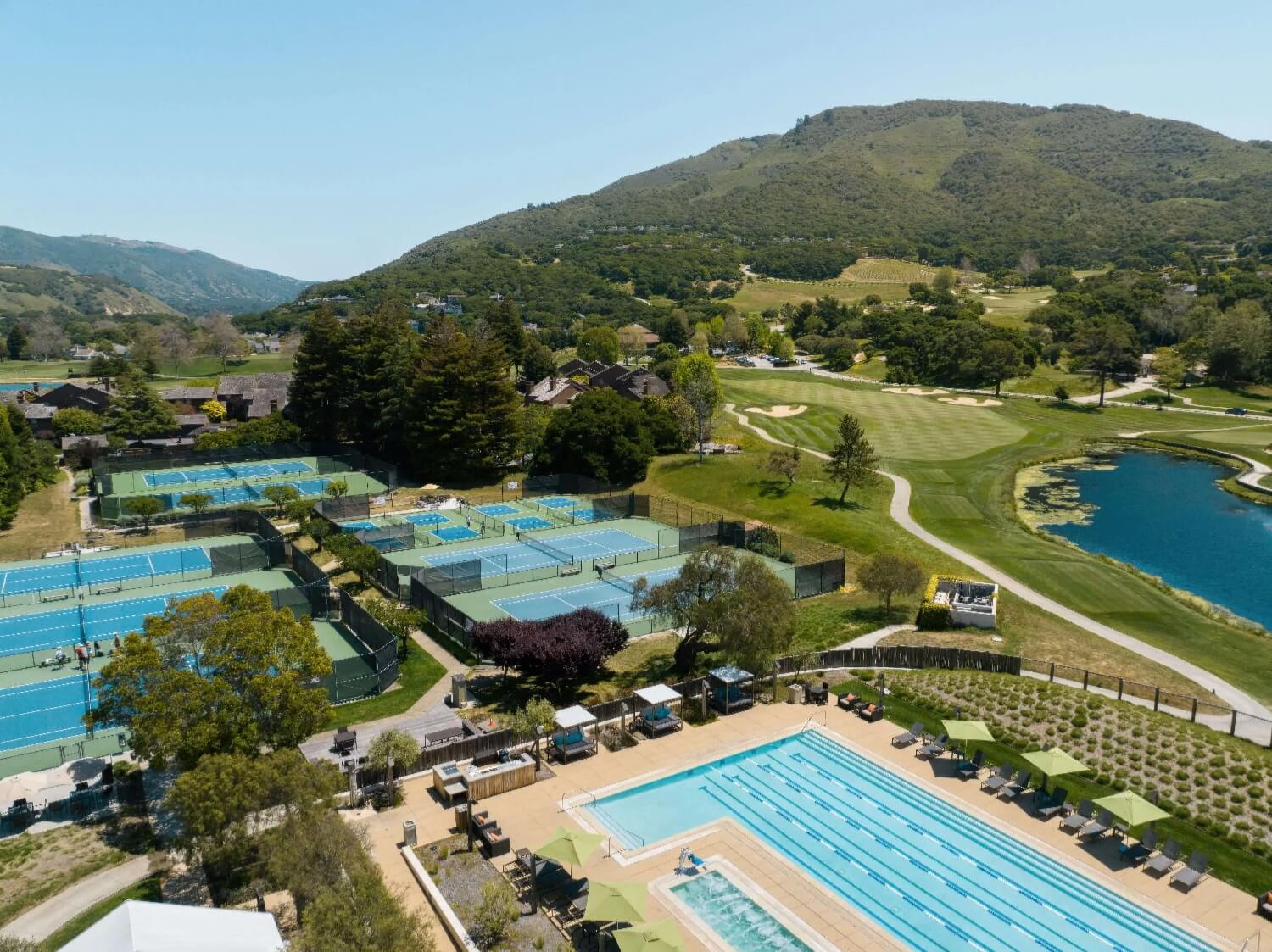 Aerial of tennis and pickleball courts, lap pool, golf fairways and lake at Carmel Valley Ranch, Carmel Valley