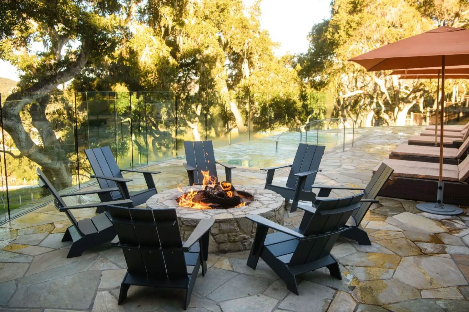 Stone fire pit ringed by six Adirondack chairs beside the pool at Carmel Valley Ranch, Carmel Valley