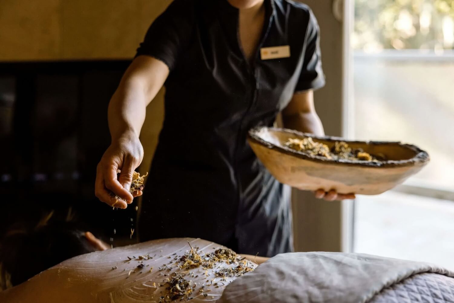 Therapist scattering dried lavender and petals over a guest's back at Spa Aiyana, Carmel Valley Ranch, Carmel Valley
