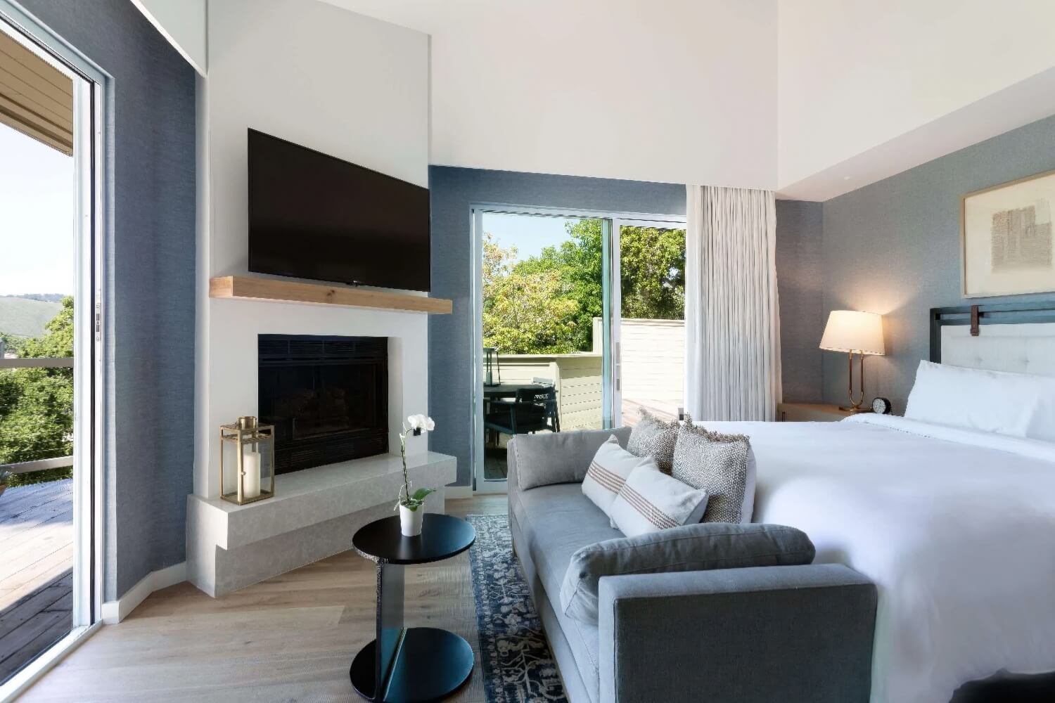 Suite with fireplace, grey sofa and deck doors opening onto oak-covered hills at Carmel Valley Ranch, Carmel Valley