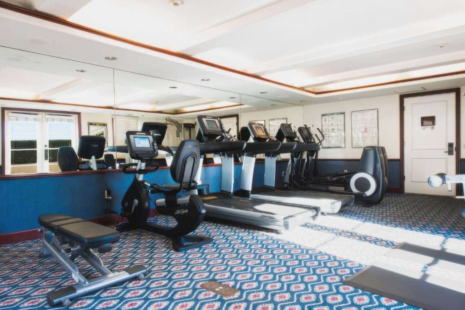 Fitness center with a treadmill and cardio row beside a mirrored wall at Harbor View Inn, Santa Barbara