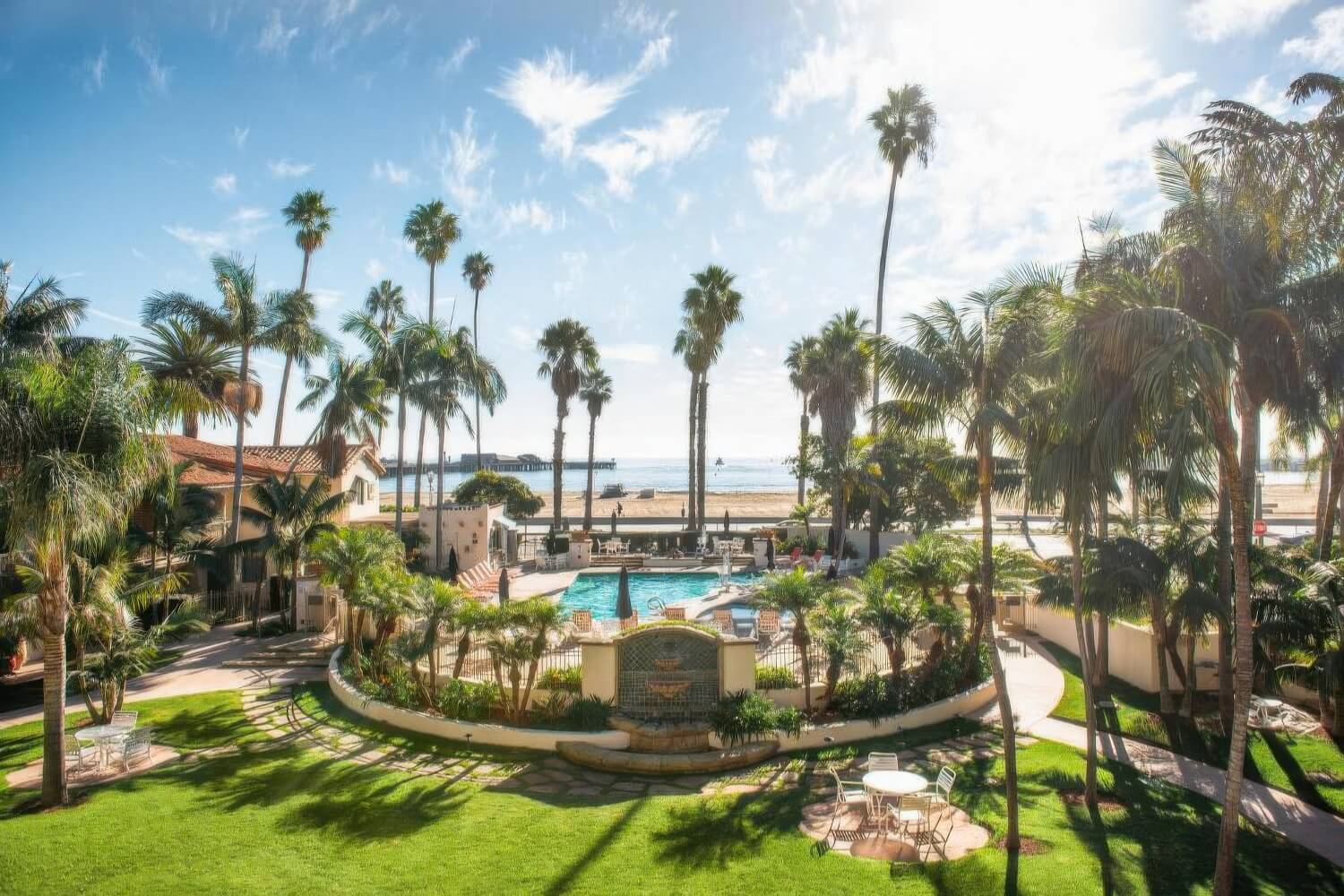 Lawns and a tiled fountain surround the pool, with West Beach beyond, at Harbor View Inn, Santa Barbara.