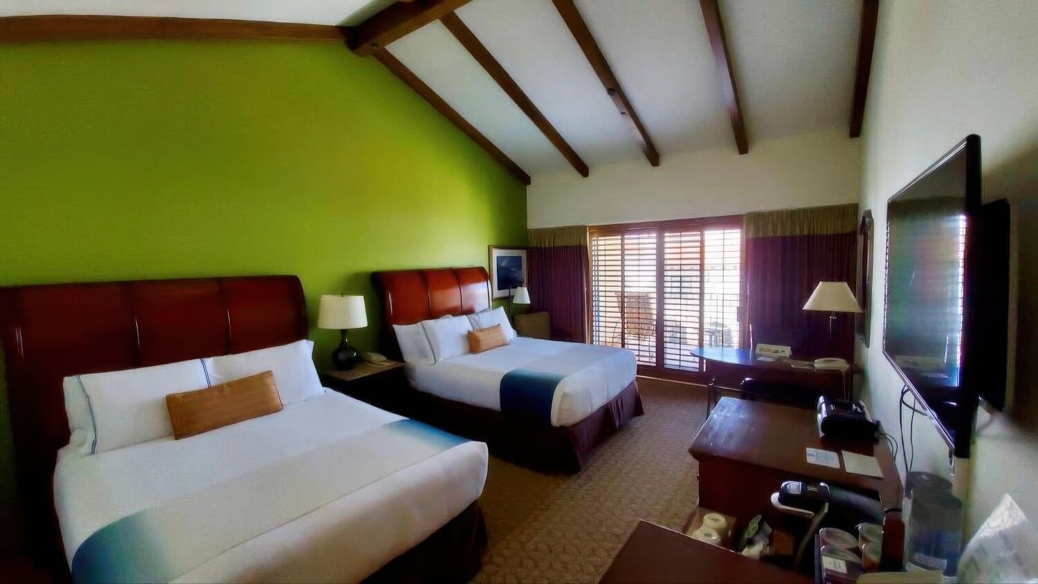 Guest room with two queen beds under a vaulted beamed ceiling at Harbor View Inn, Santa Barbara.