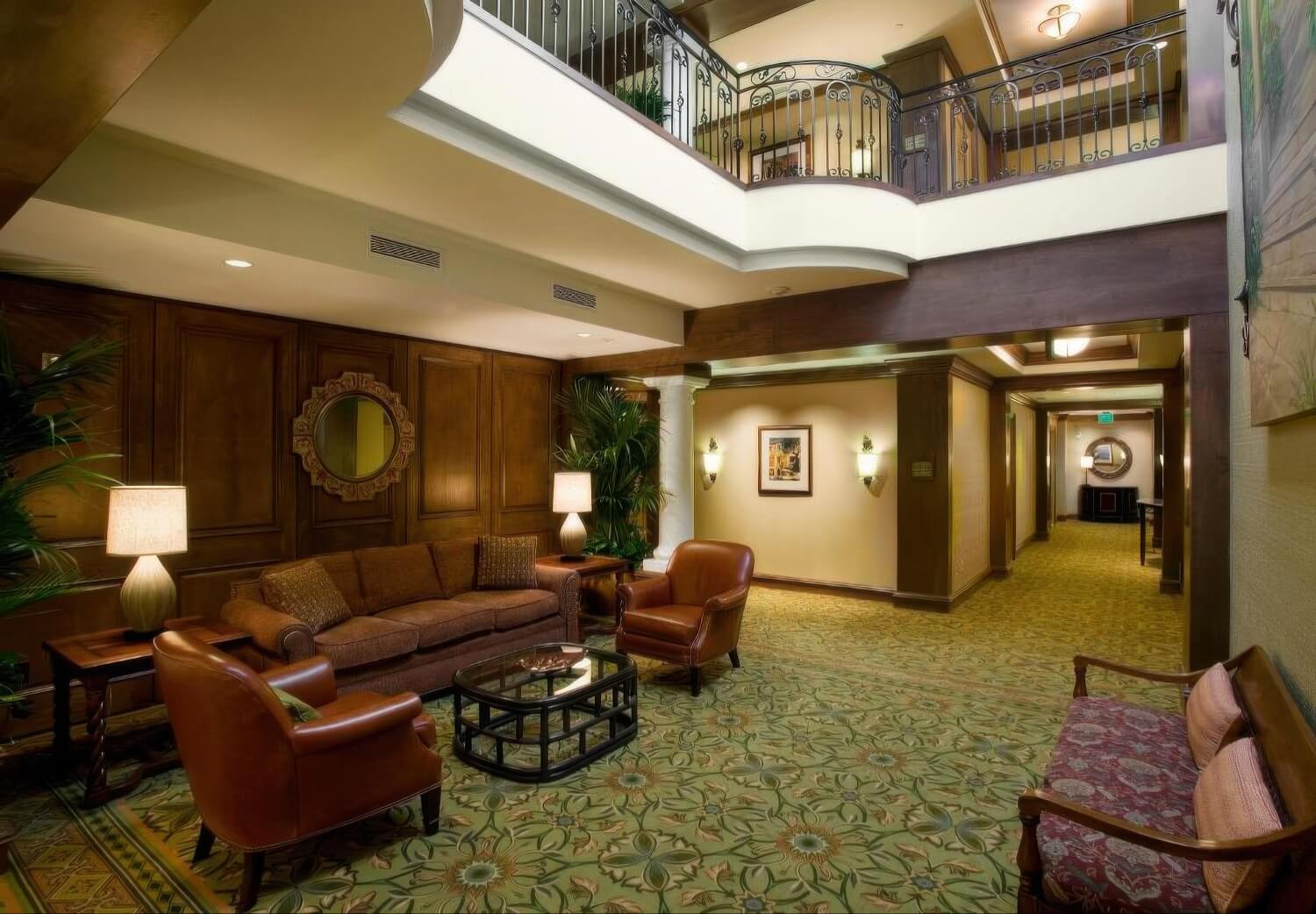 Two-story lobby with wood paneling and a wrought-iron gallery rail at Harbor View Inn, Santa Barbara.
