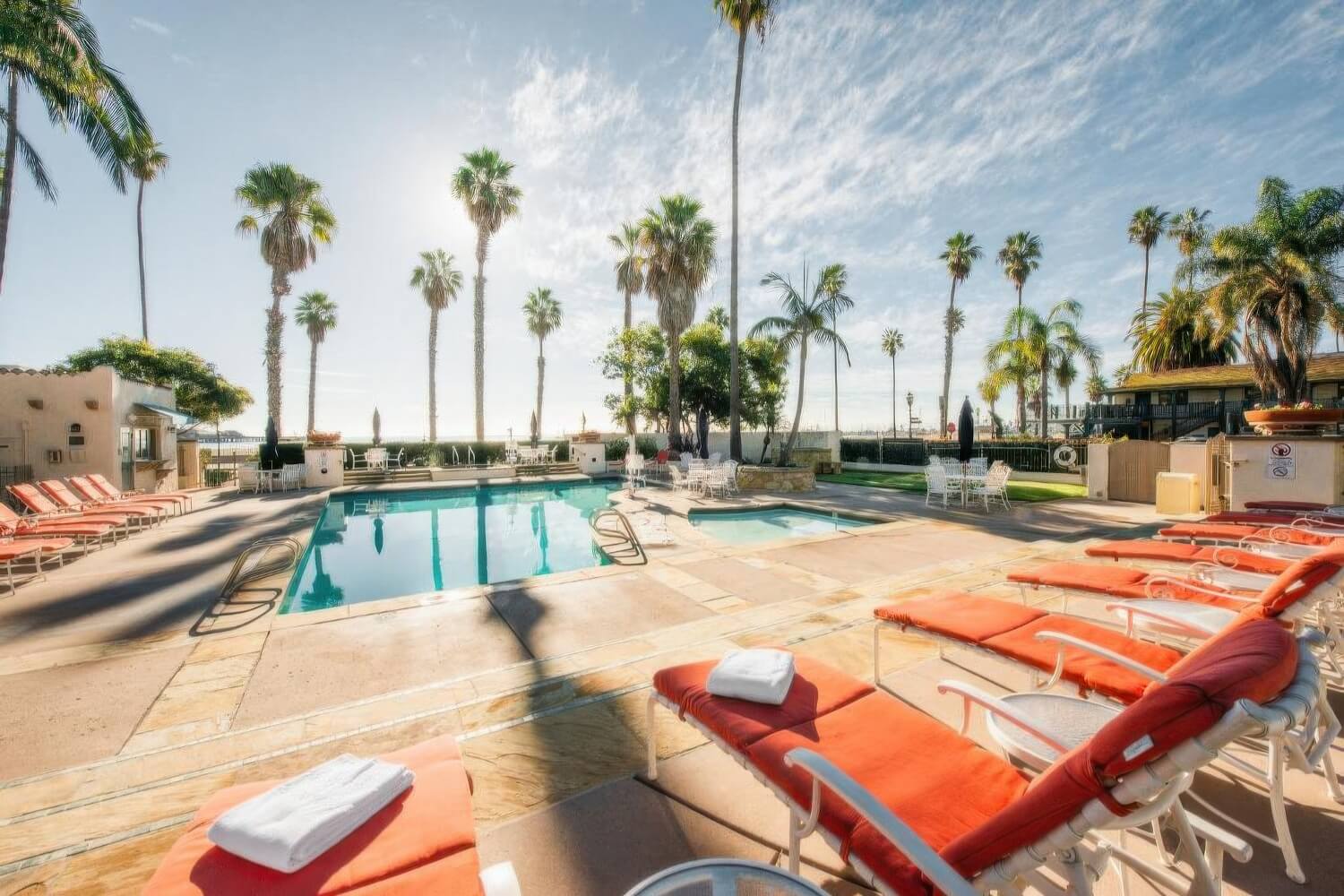 Heated outdoor pool lined with orange loungers, facing the ocean at Harbor View Inn, Santa Barbara.