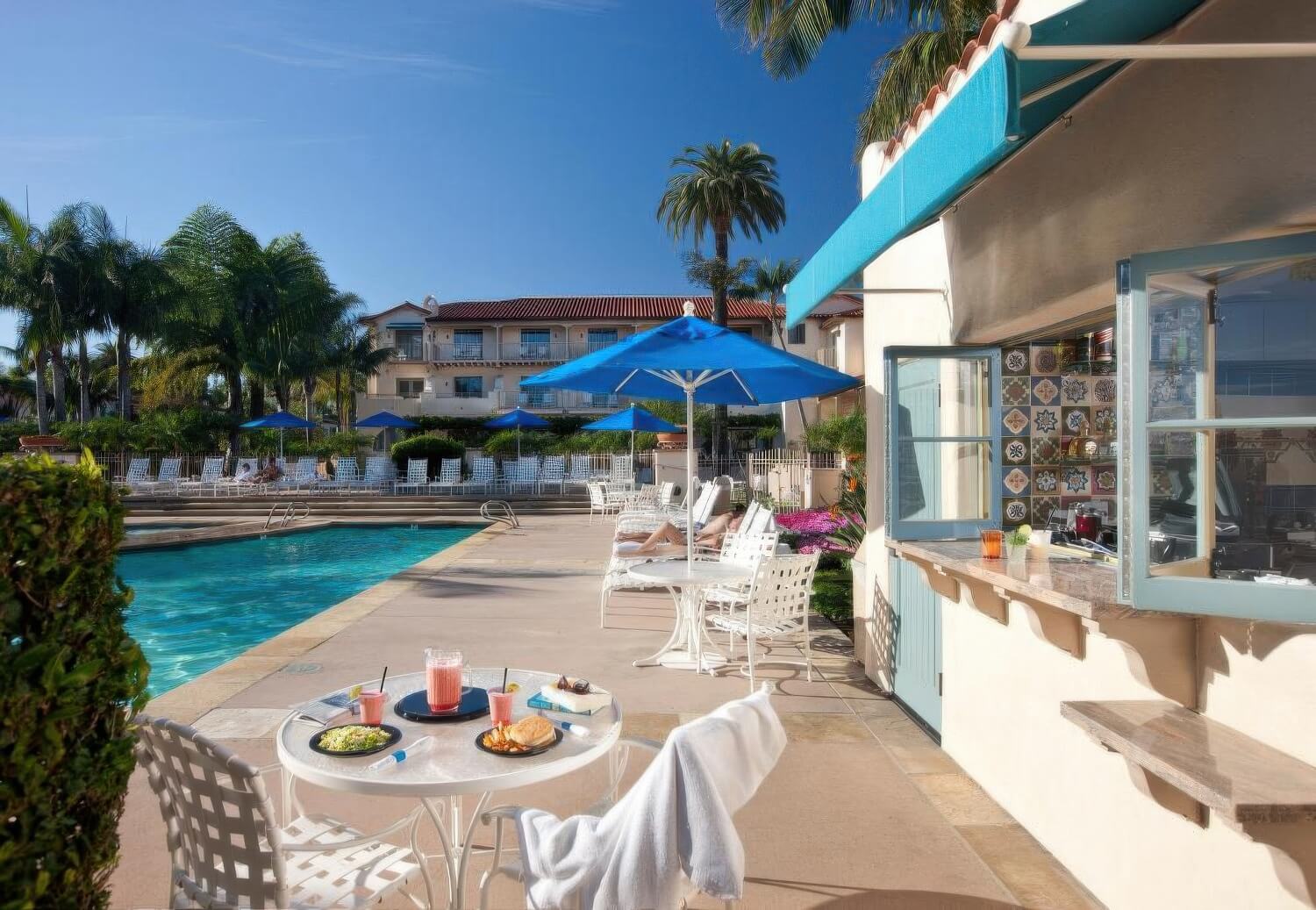 Poolside café window trimmed with hand-painted Spanish tiles under a blue awning at Harbor View Inn, Santa Barbara.