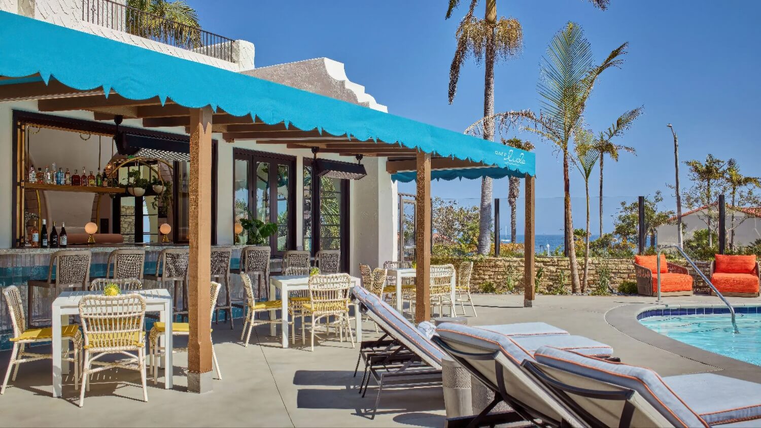 Café Lido's turquoise-awning poolside terrace with rattan dining chairs and a walk-up bar at Mar Monte Hotel, Santa Barbara.