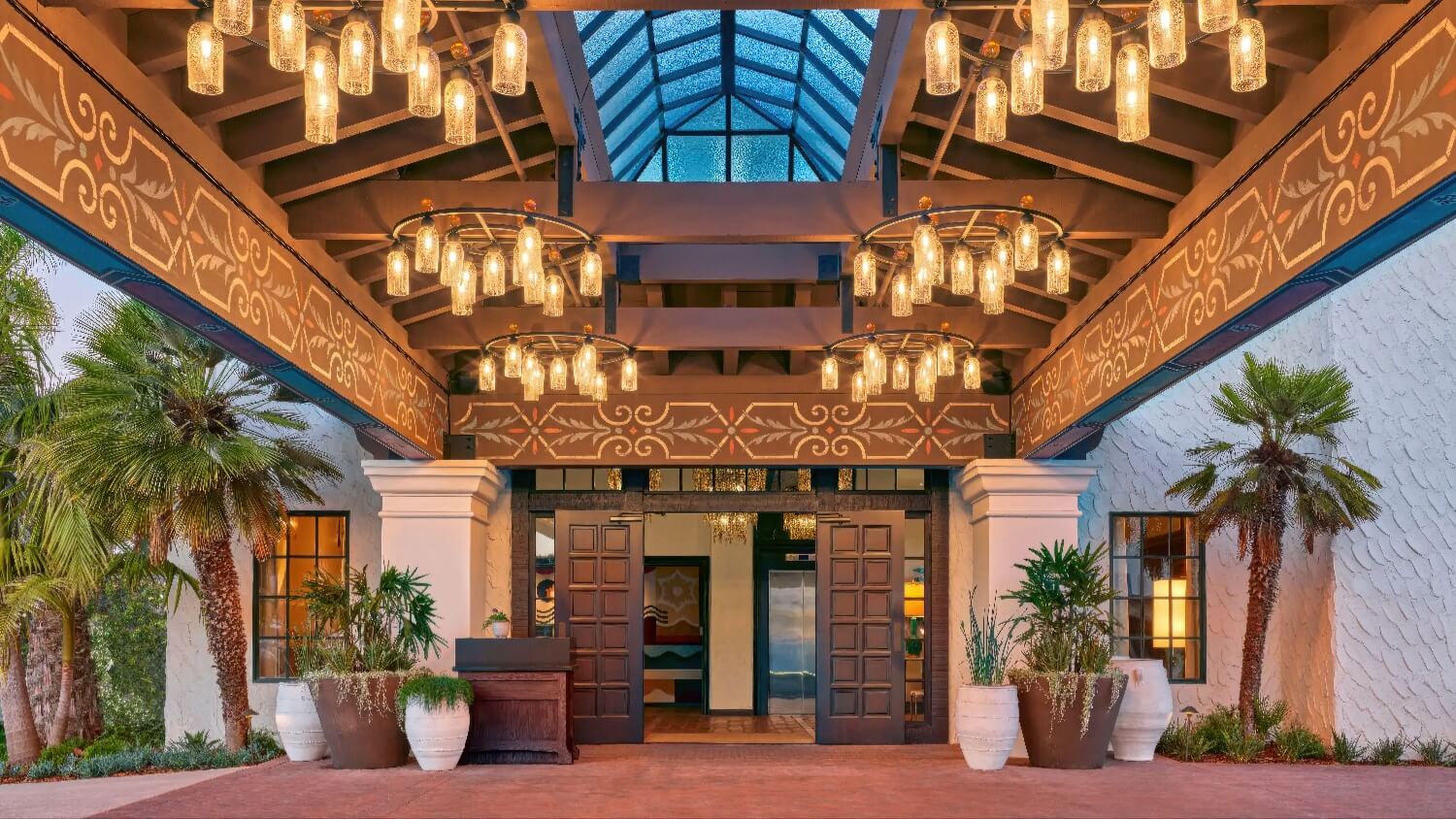 Porte-cochère entrance with stenciled beams and glass-jar chandeliers at Mar Monte Hotel, Santa Barbara.