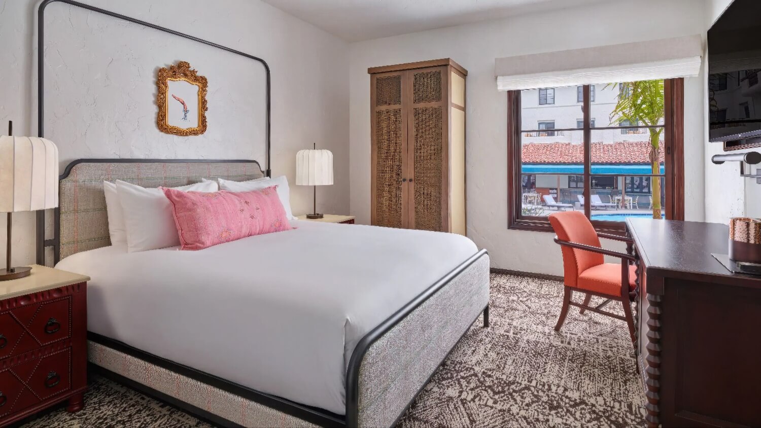 King Deluxe room with cane wardrobe and a window overlooking the pool deck at Mar Monte Hotel, Santa Barbara.