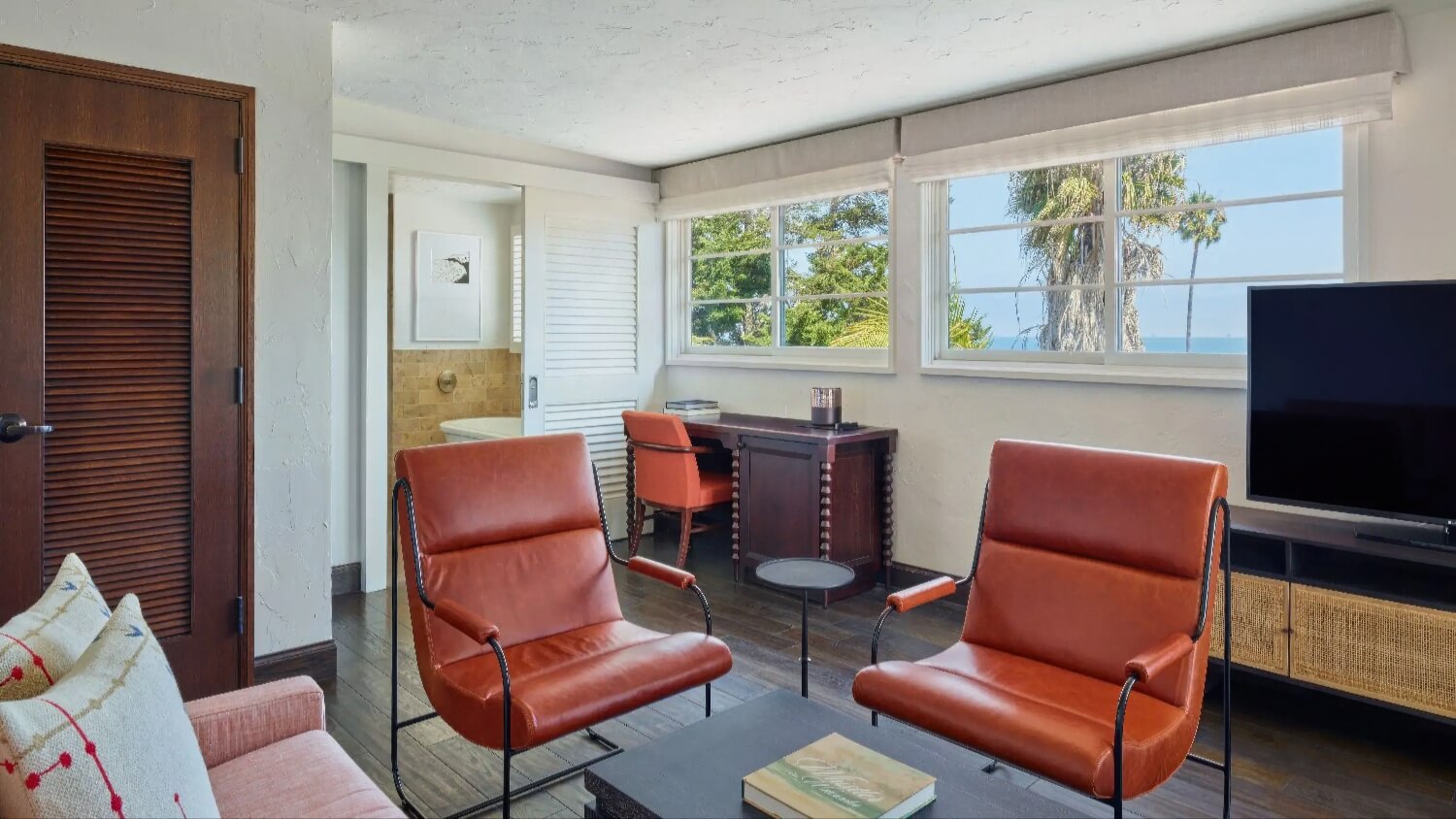 Living room of the Santa Maria Junior Suite with leather armchairs and ocean-view windows at Mar Monte Hotel, Santa Barbara.