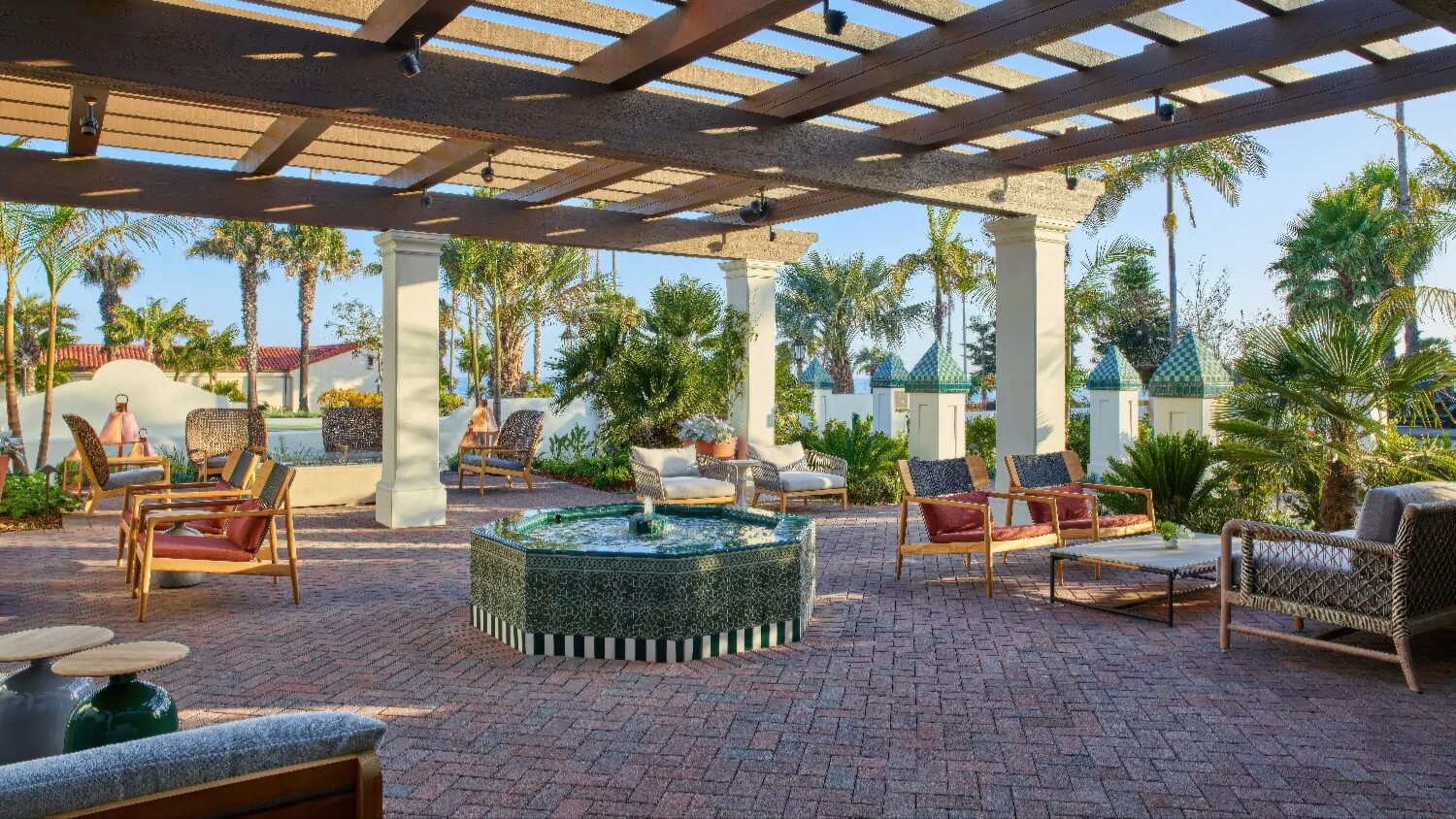 Pergola-shaded terrace with a green-tiled fountain and lounge seating at Mar Monte Hotel, Santa Barbara.