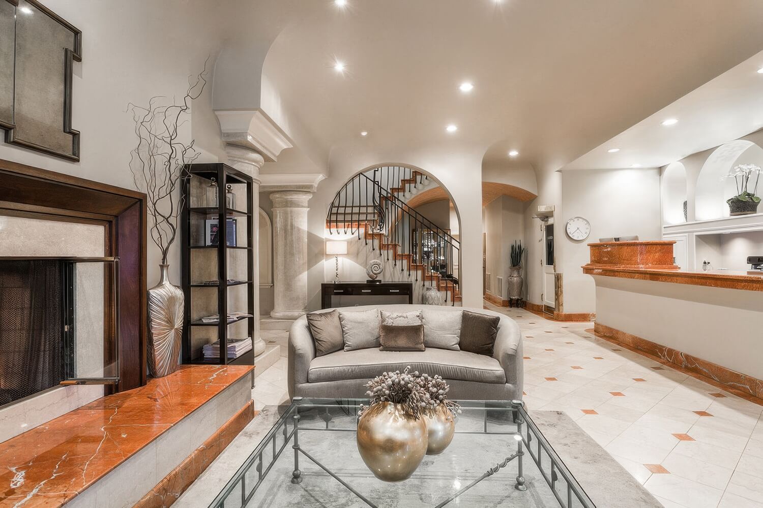 Lobby with marble-trimmed fireplace, curved gray sofa, stone columns and front desk at the Montecito Inn, Montecito