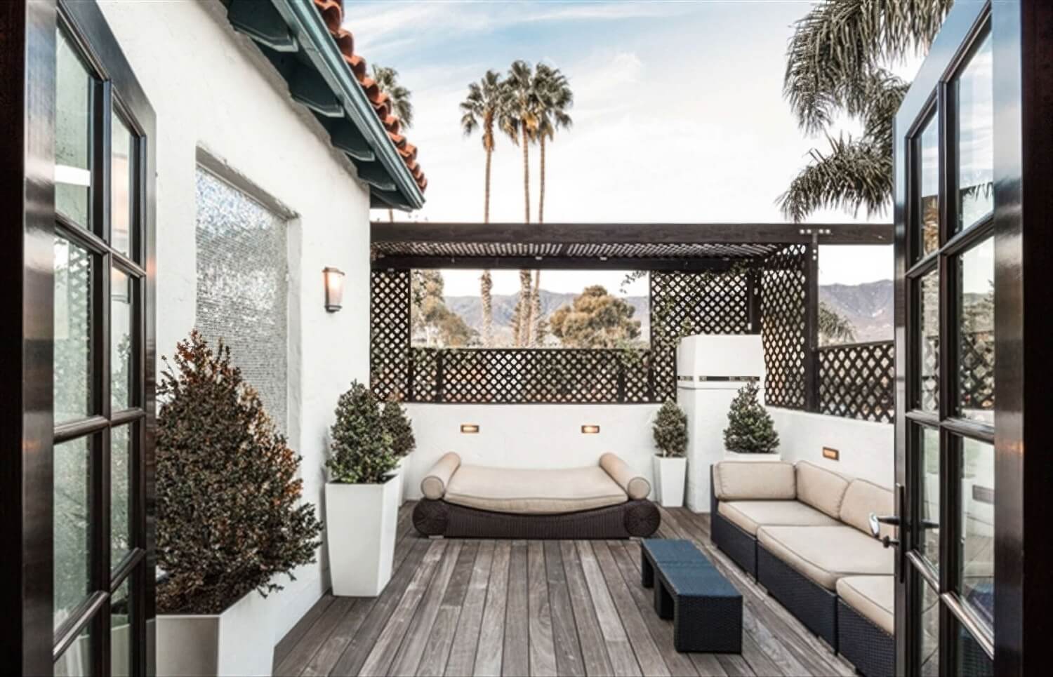 Private rooftop terrace with lattice pergola, wicker daybed, sofa and Santa Ynez mountain views at the Montecito Inn, Montecito