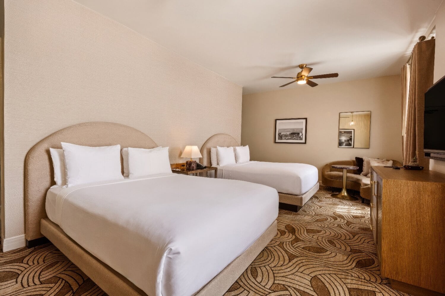 Two-queen guest room with arched headboards, ceiling fan and art-deco patterned carpet at the Montecito Inn, Montecito