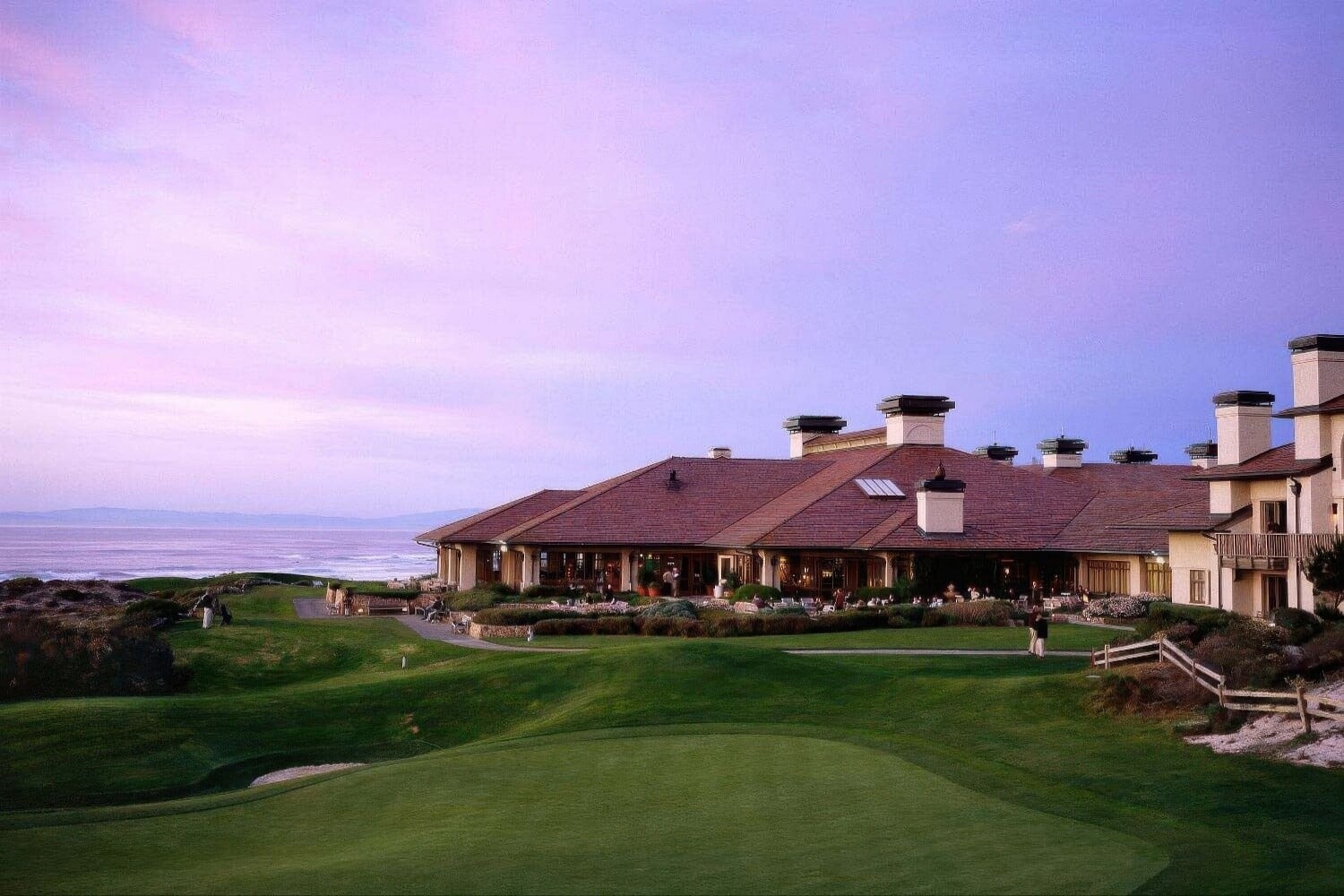 Red-roofed resort buildings and terrace above the fairway at dusk at The Inn at Spanish Bay, Pebble Beach