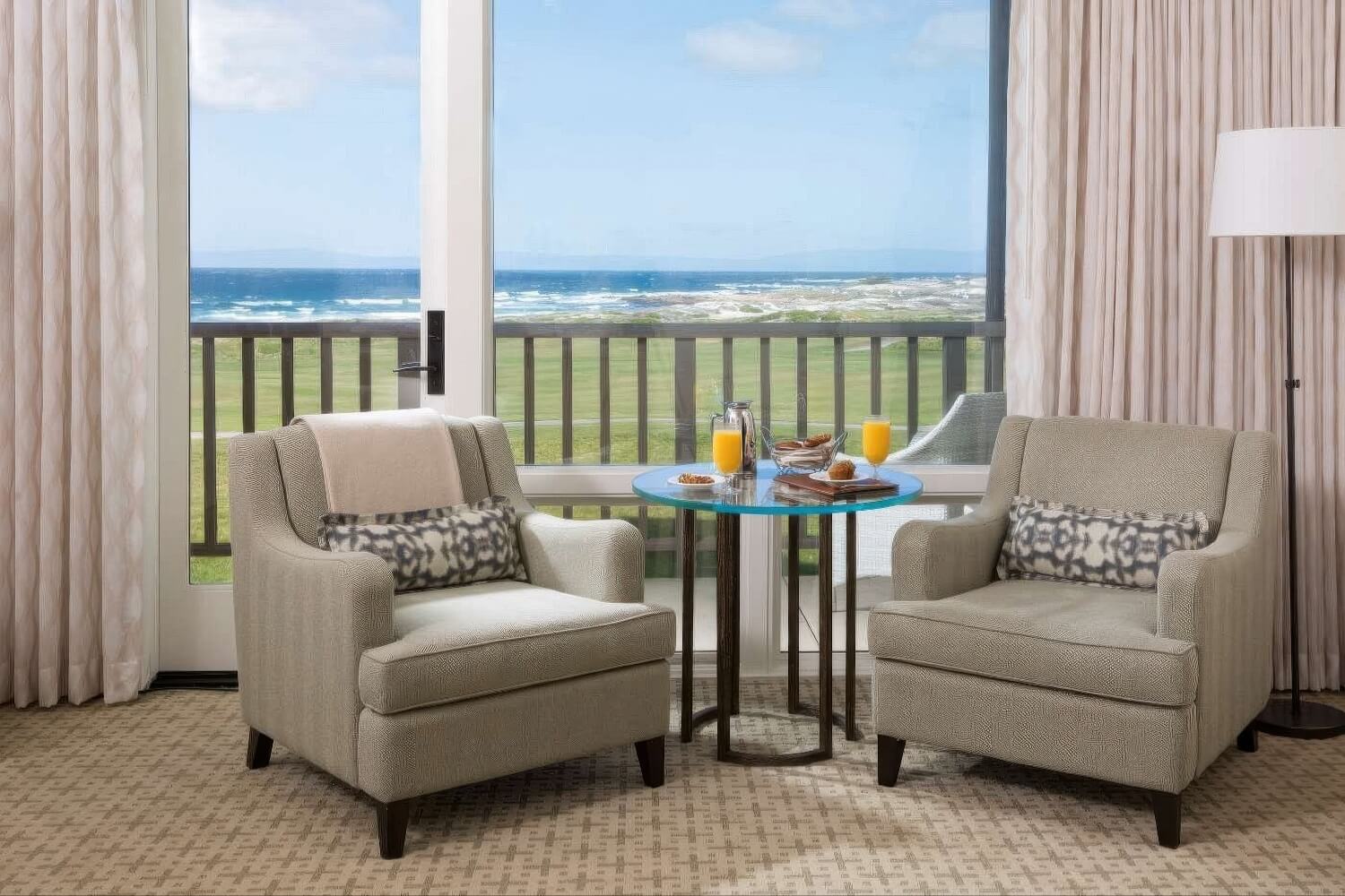 Armchairs and breakfast table at window over fairway and ocean at The Inn at Spanish Bay, Pebble Beach